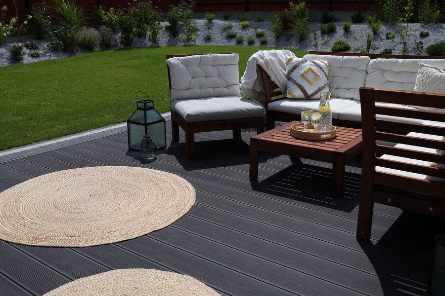 taras wykonany z kompozytowej deski tarasowej z drewnianymi meblami i tkanymi dywanami